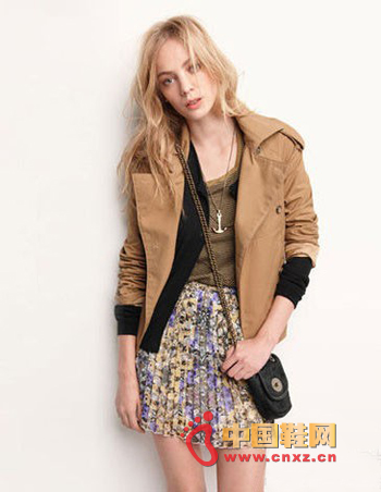 In a camel-coloured trench coat, a black sweater and a khaki T-shirt, with a pleated skirt full of florals