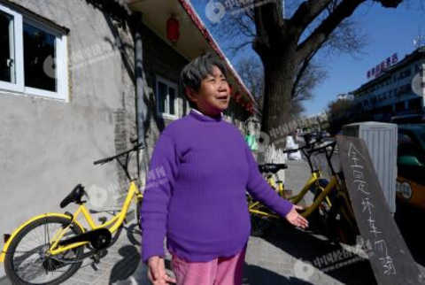 P47-1 A resident living near the Nanheyan Street assisted the ofO offline operators in placing some of the damaged bicycles in a centralized position and making a sign.