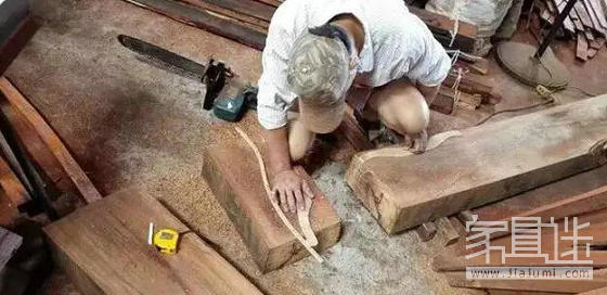 Mahogany furniture production: the master compares the length of the wood with a small sample