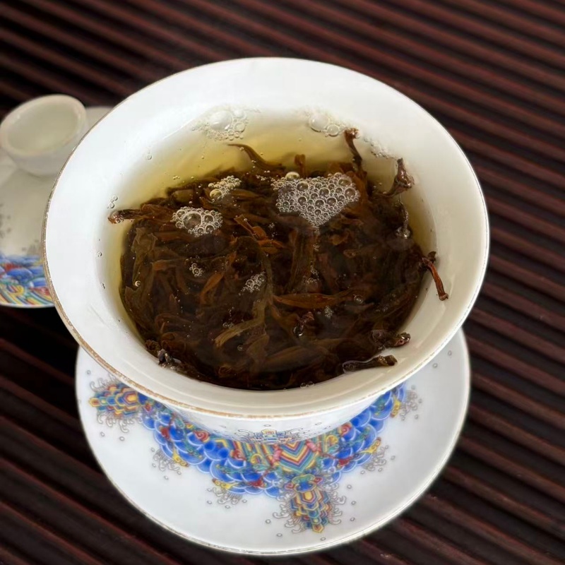 Steeped spring sun dried black tea leaves inside decorated porcelain gaiwan Steeped spring sun dried black tea leaves inside decorated porcelain gaiwan
