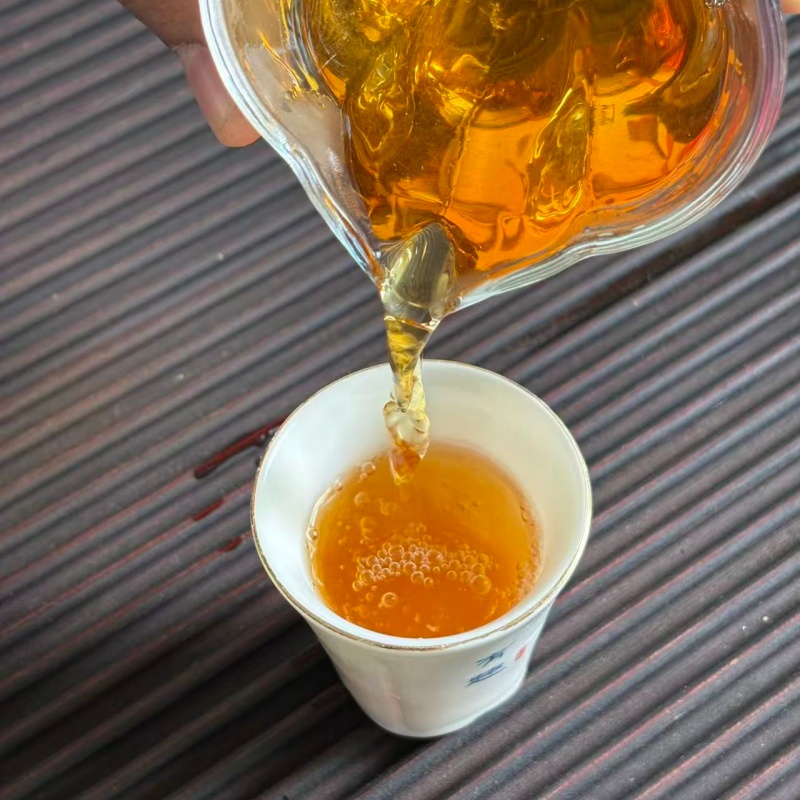 Pour sun red black tea from glass gongdao pitcher into small tasting cup Pour sun red black tea from glass gongdao pitcher into small tasting cup