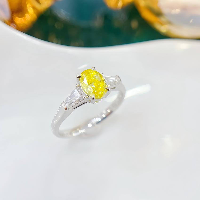 Angled view of 18K white gold yellow oval ring with step cut baguette side diamonds