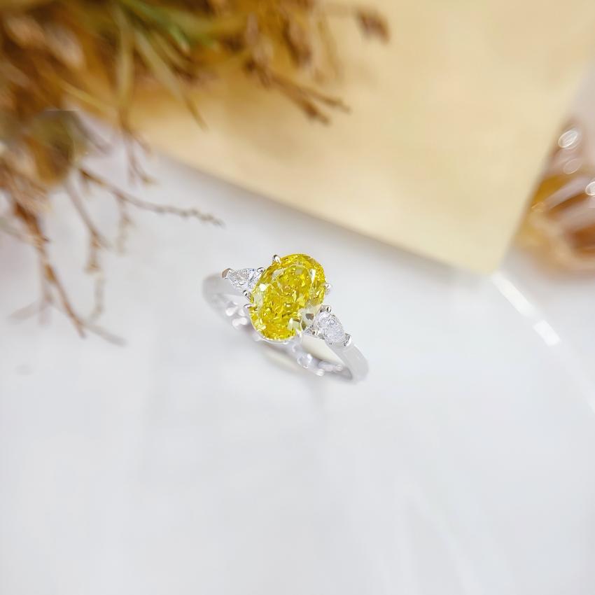 Front view of a Fancy Vivid Yellow oval trilogy ring with outward facing pear diamonds