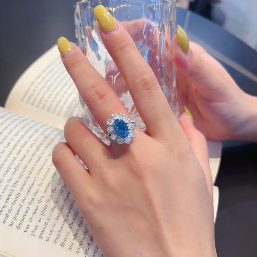 Oval blue diamond halo ring worn on hand