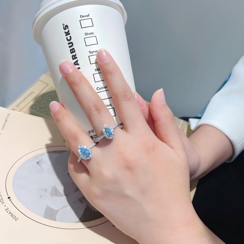 Petite blue halo rings worn on hand for scale comparison