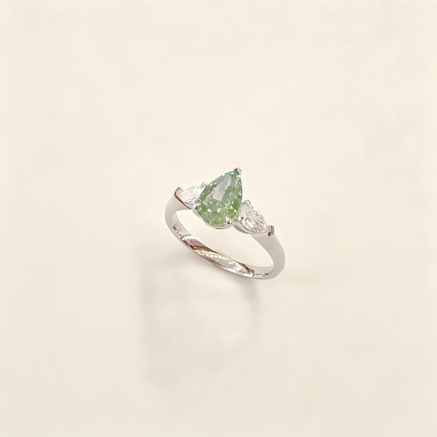 Angled view of green pear lab diamond ring with twin pear side stones and polished white gold shank