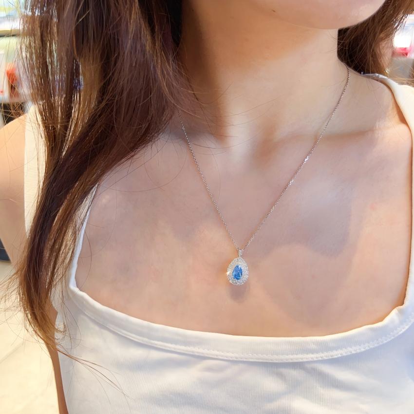 Pear vivid blue halo pendant worn on necklace