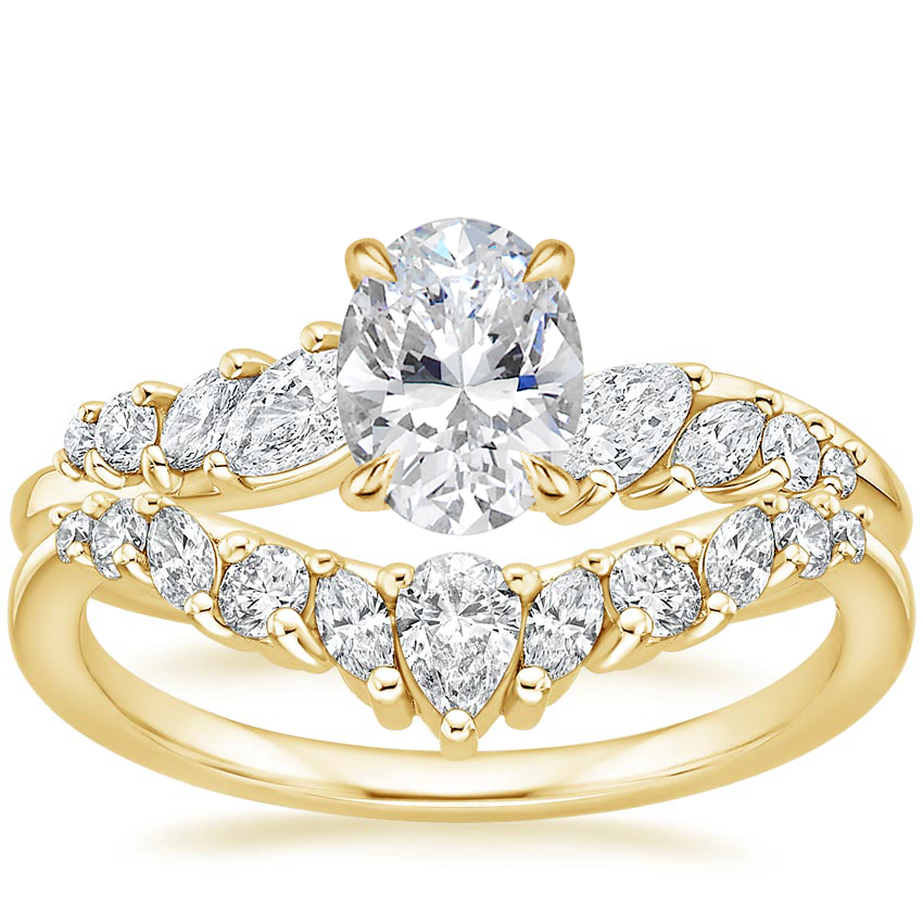 Yellow gold lab grown bridal set with oval center stone and an infinity twist band featuring half pave and half polished gold