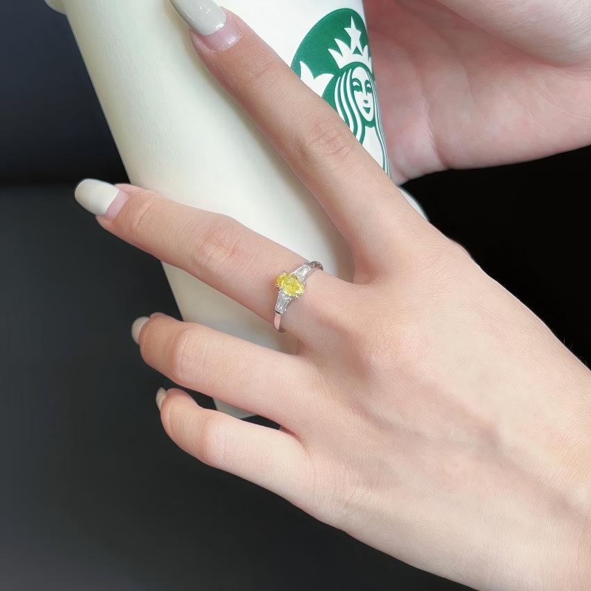 Yellow oval lab diamond ring with tapered baguette sides shown on hand