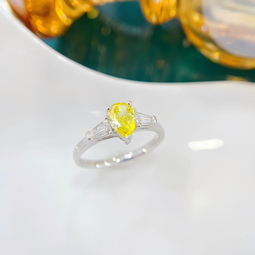 Front view of a yellow pear lab diamond ring with step cut baguette side stones