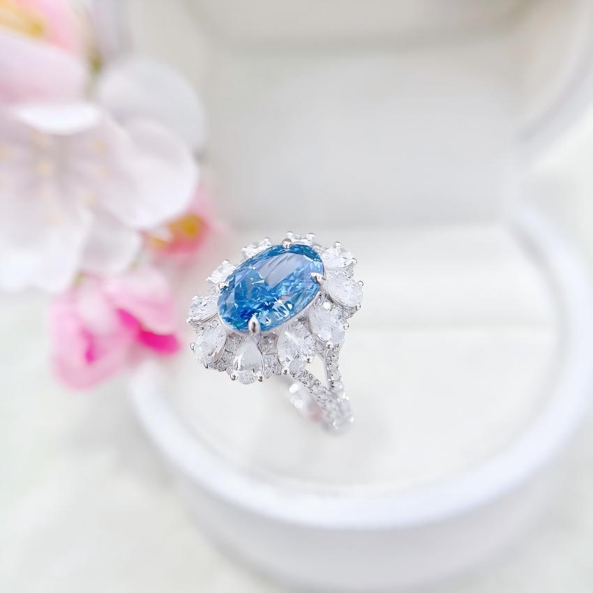 Close view of oval blue center stone with white halo stones