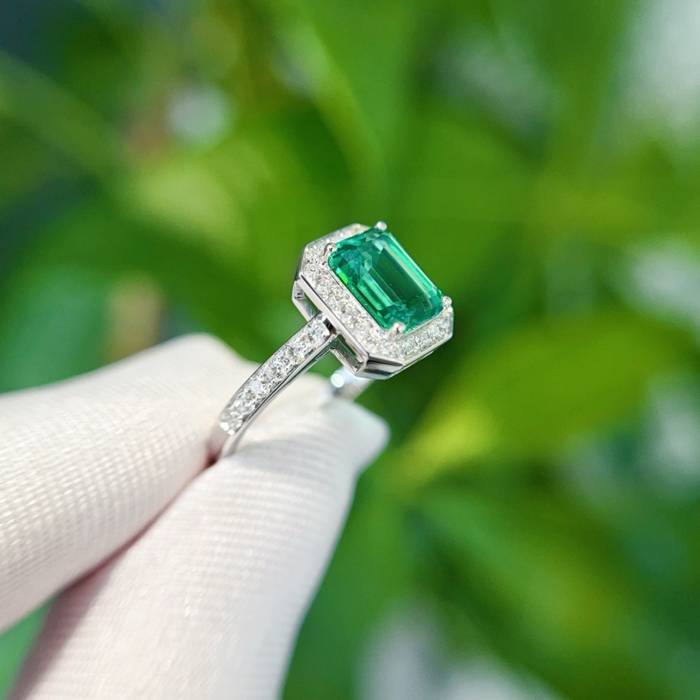 Macro detail of hand-set lab emerald and micro-pave halo