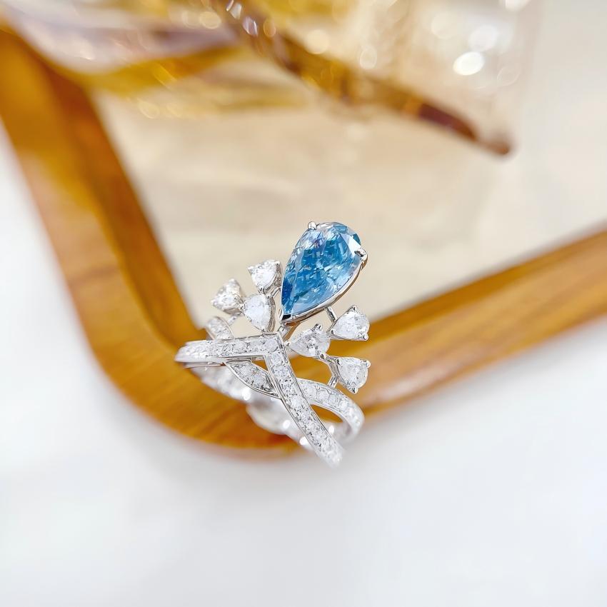 Close up pear blue diamond ring with white floral side stones