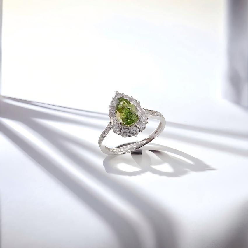 Angled view of green pear lab diamond halo ring with baguette side stones and pave shoulders