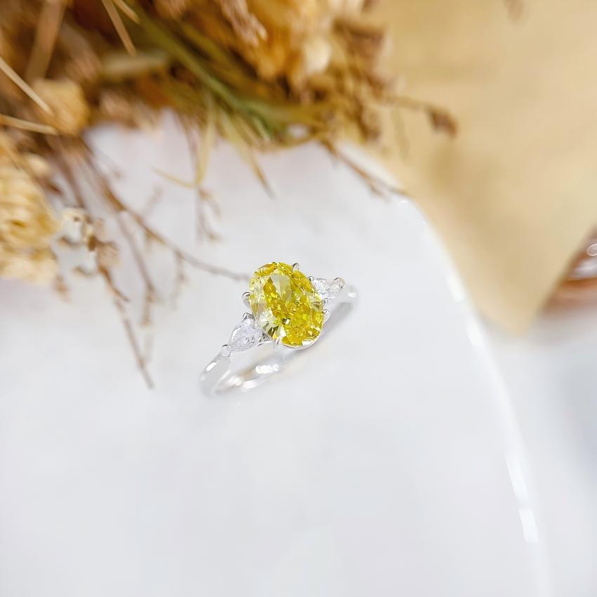 Angled view of a yellow oval lab diamond ring with matched pear side diamonds