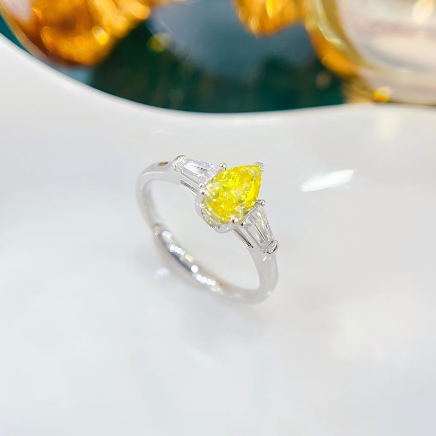 Angled view of a yellow pear diamond ring with mirrored tapered baguette shoulders