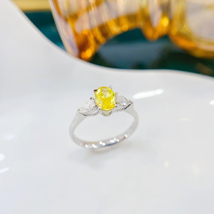 Angled view of a yellow oval lab diamond ring with matched pear side stones