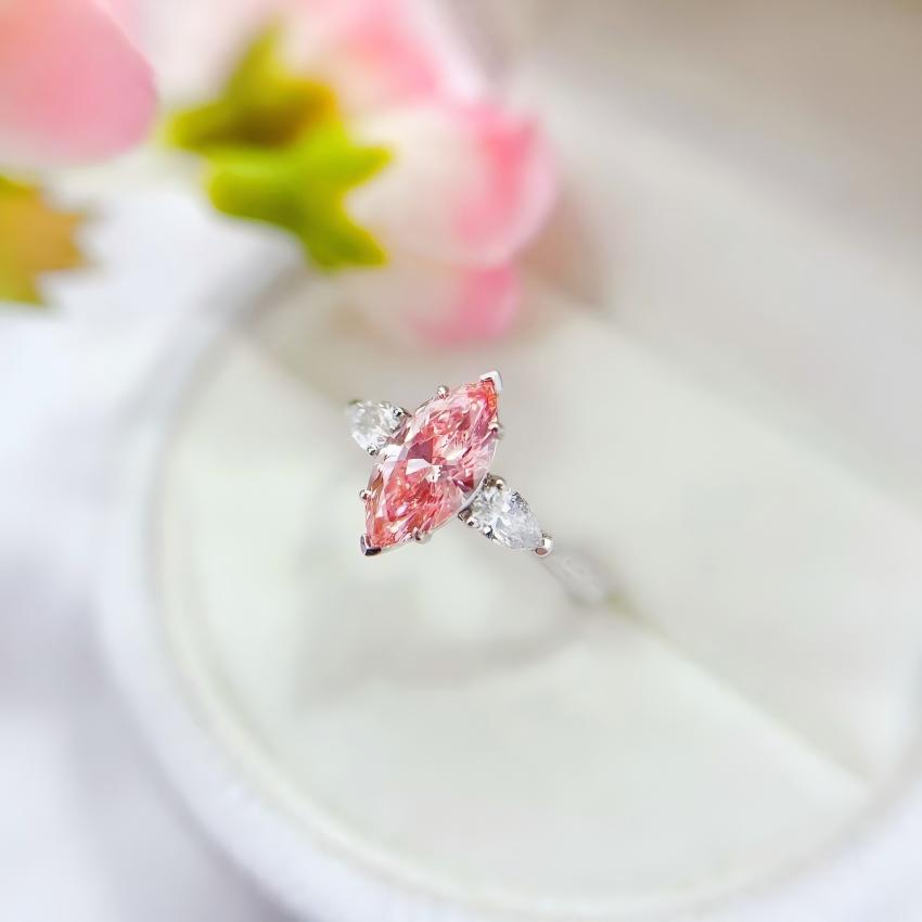 Angled view of a pink marquise lab diamond ring with two pear-shaped side diamonds