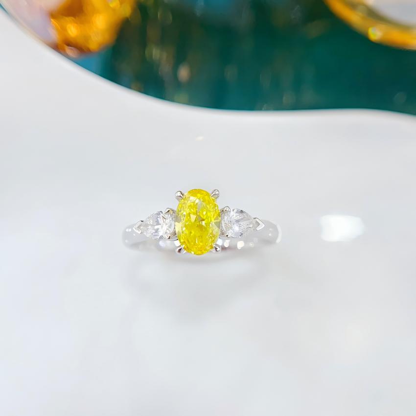 Front view of an oval yellow lab diamond ring with pear side diamonds